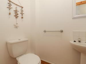 a white bathroom with a toilet and a sink at Coastal Nest 30 Union Street in Seahouses +17 photos