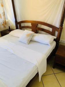 2 bedden in een kamer met witte lakens en kussens bij Ltorec in Nyali