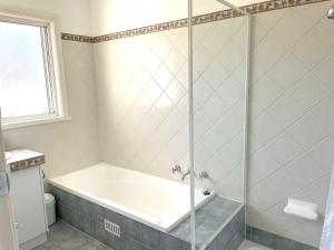 a bathroom with a tub and a glass shower at The Whitehouse in Emu Bay +15 photos