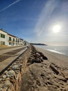 a beach with a stone wall and the ocean at Apartamento en playa de Altafulla in Altafulla