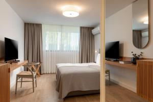 um quarto de hotel com uma cama e uma secretária com dois monitores em Hiddenbay Teos Sığacık Hotel, Spa and Restaurants em Seferihisar