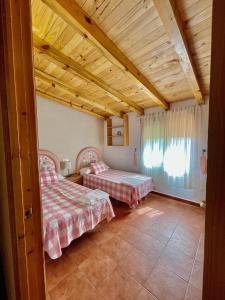 1 dormitorio con 2 camas en una habitación con techos de madera en Cortijo El Pino, en Cortijos Nuevos