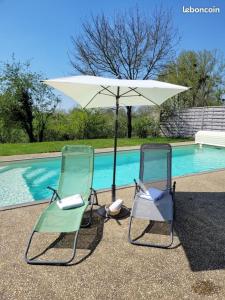 duas cadeiras e um guarda-sol ao lado de uma piscina em La maisonnette em Moncoutant