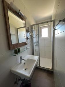 ein Bad mit einem Waschbecken, einer Dusche und einem Spiegel in der Unterkunft Pension Monika, Kaprun, incl Summercard in Kaprun