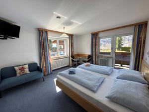 a bedroom with two beds and a couch and a television at Pension Monika, Kaprun, incl Summercard in Kaprun