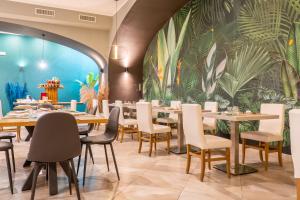 a restaurant with tables and chairs and a mural of plants at Corte San Lorenzo in Sant'Egidio del Monte Albino