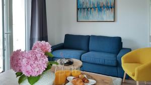 uma sala de estar com um sofá azul e uma mesa com flores cor-de-rosa em Marisa Apartments Hvar II em Hvar