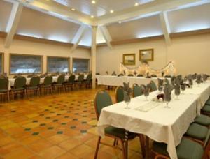 un salón de banquetes con mesas blancas y sillas verdes en Merced Inn & Suites, en Merced