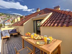 einen Holztisch mit Essen auf dem Balkon in der Unterkunft Canto Idílico by LovelyStay in Funchal