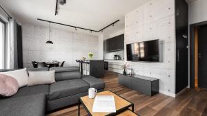a living room with a gray couch and a kitchen at Flatbook - City Center Apartments Brabank with Parking in Gdańsk