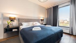a bedroom with a blue bed with a large window at Flatbook - City Center Apartments Brabank with Parking in Gdańsk