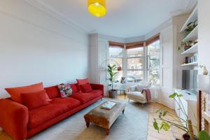 a living room with a red couch and a table at Charming 1 bedroom apartment in Finsbury Park in London