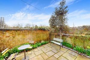 a patio with a bench and a table next to a brick wall at Charming 1 bedroom apartment in Finsbury Park in London