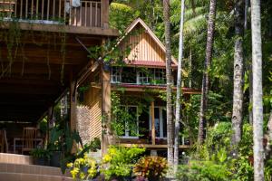 a house with a wrap around porch with trees at Air Manis Hillside Villa Cafe & Resto in Padang