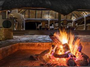 Sable Ranch Bush Lodge في بريتس: حفرة حريق مع النار في غرفة