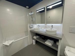 a bathroom with two sinks and a tub and a mirror at Best Western Hôtel Royan Océan in Royan