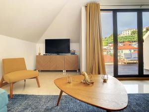 ein Wohnzimmer mit einem Tisch und einem TV in der Unterkunft Canto Idílico by LovelyStay in Funchal