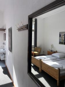 ein Spiegel, der ein Schlafzimmer mit einem Bett und einem Stuhl reflektiert in der Unterkunft Die Fabrik - baxpax Hotel in Berlin