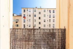 a building behind a fence with a building in the background at MY CASA - RISSO - Comfortable 3 Bedrooms with balcony in Nice