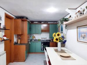 uma cozinha com armários verdes e um vaso de flores num balcão em Casa Zila em Finale Ligure