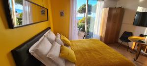 a bedroom with a bed with yellow walls and a window at Studio de la plage - Mer, Terrasse et garage in Cagnes-sur-Mer