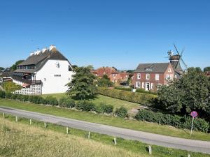 a house and a road with houses and a windmill at Haus Lith - Fewo Olesen in Nordstrand