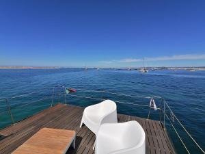 dos sillas blancas sentadas en la cubierta de un barco en Barco Casa Fuzeta, en Fuseta