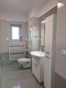 a white bathroom with a toilet and a sink at Andrea Villa Hévíz II in Hévíz