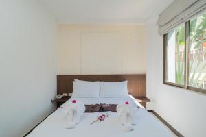 1 dormitorio con 1 cama con sábanas blancas y ventana en Destination Patong en Patong Beach