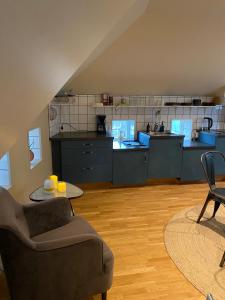 uma cozinha com armários azuis, um sofá e uma mesa em Lomma Station Inn Loft em Lomma