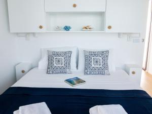Una cama blanca con almohadas azules y un libro. en Barco Casa Fuzeta, en Fuseta