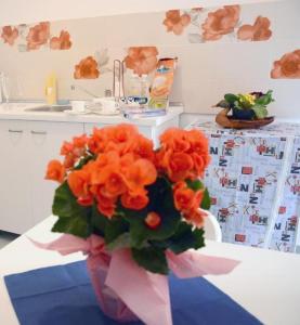 eine Vase mit orangefarbenen Blumen auf einem Tisch in der Küche in der Unterkunft Grigio Pesca in Salerno