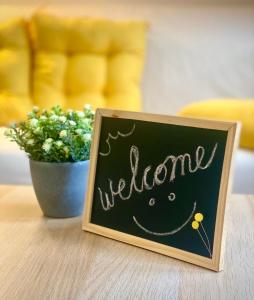 a sign that says welcome next to a vase of flowers at Rainbow House Rooms in Maribor