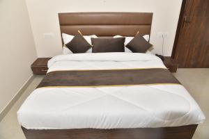 Schlafzimmer mit einem großen Bett mit einem Kopfteil aus Holz in der Unterkunft APEX HOTEL in Amritsar