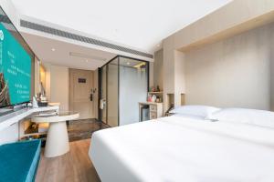 a bedroom with a large white bed and a tv at Houhai Hotel in Beijing