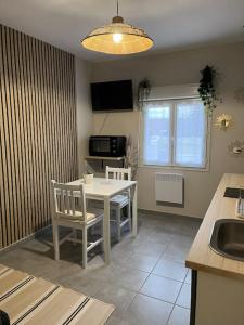 a kitchen with a table and chairs and a sink at Duplex paisible à la campagne in Relans +17 photos