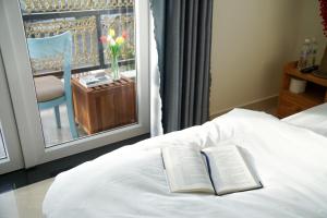 um livro sentado em cima de uma cama com uma janela em Môn Bạc Home em Da Lat