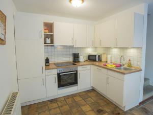 une cuisine avec des armoires blanches et un évier dans l'établissement Ferienhaus Gerth, FeWo Vermittlung Nordsee, à Dangast