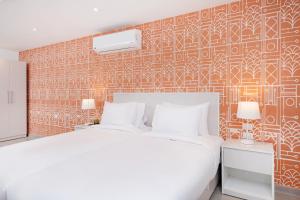 カイロにあるBrassbell apartments by the Pyramidsの白いベッドとオレンジ色の壁が備わるベッドルーム1室が備わります。