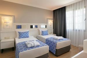 a bedroom with two beds with blue and white sheets at Euphoria Barbaross Beach Resort in Kızılot
