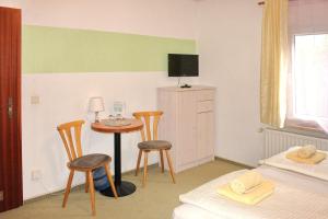 a bedroom with a table and two chairs and a television at Pension An der Kamske, DZ 3 in Lübbenau