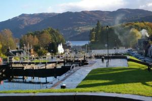 a marina with cars parked next to a body of water at Loch Ness Gate House in Fort Augustus