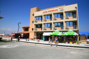 a building with a market with umbrellas in front of it at Hotel Promenada in Mamaia