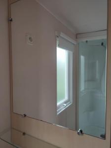 a mirror in a bathroom with a window at Mobil-home Alsace in Biesheim
