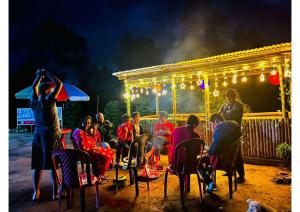 een groep mensen die 's nachts in stoelen op een podium zitten bij Twillight hometsay in Darjeeling