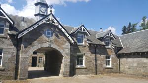 Un antiguo edificio de piedra con una torre de reloj en la parte superior. en The Bothy, Gallin, Glenlyon, Perthshire, en Bridge of Balgie