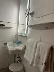 a bathroom with a sink and a toilet and towels at Hotel Sommerhaus Garni am See in Bodman-Ludwigshafen