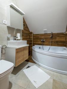een badkamer met een bad, een toilet en een wastafel bij Velika Recepcija 10 in Zlatibor