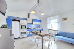 una cucina con armadi blu, tavolo e divano blu di [Idromassaggio & BBQ]wifi, relax e private parking a Sirolo