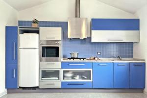 een keuken met blauwe kasten en een witte koelkast bij [Idromassaggio & BBQ]wifi, relax e private parking in Sirolo